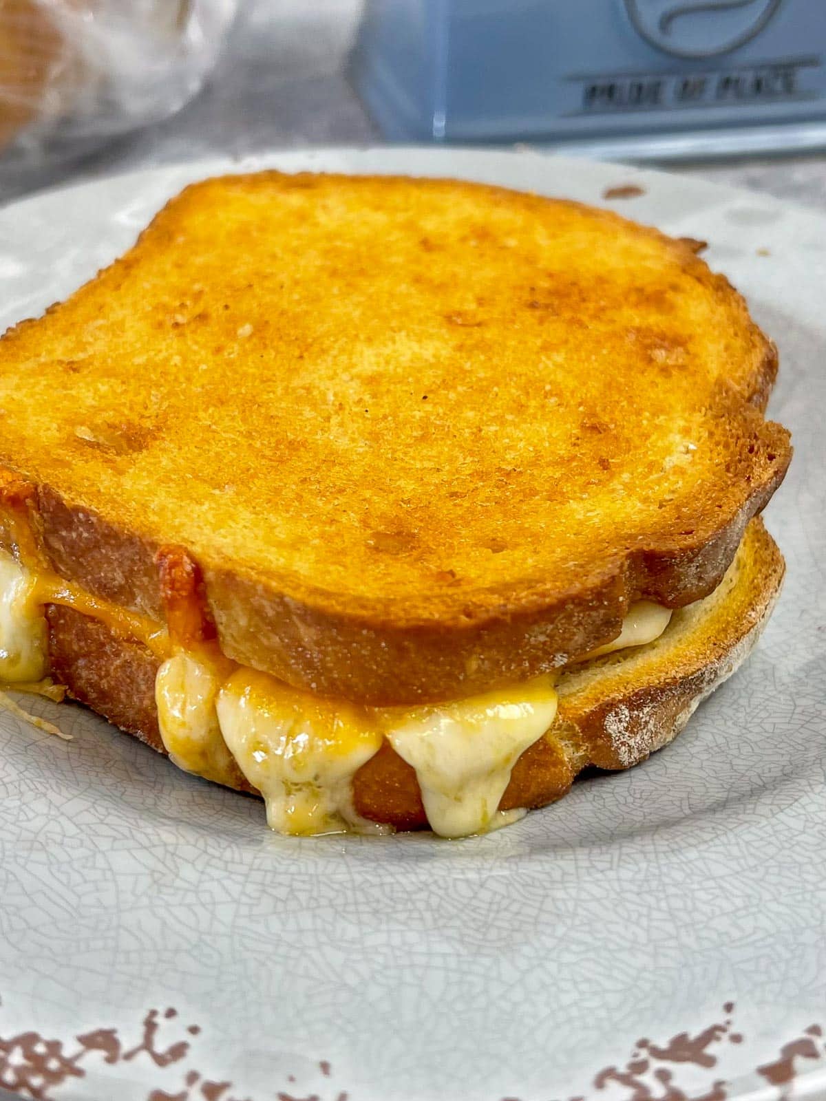 Air Fryer Grilled Cheese Sandwich on a gray plate with melty cheese coming out of the sides of the sandwich.