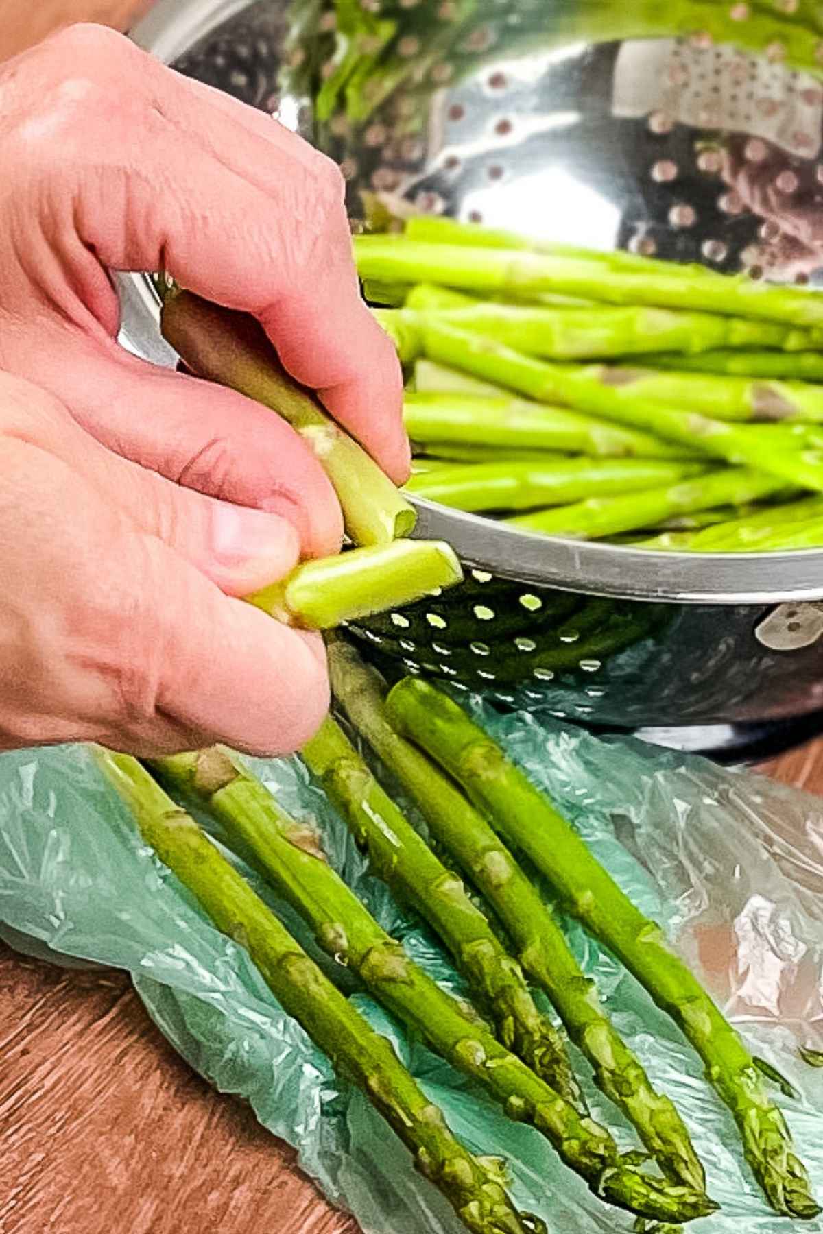 A pair of hands snapping an asparagus spear in half.