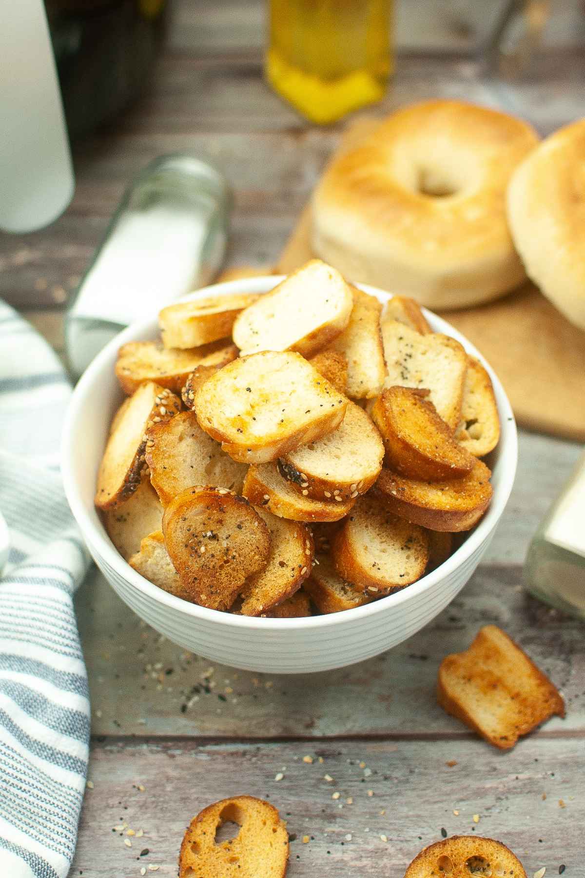 Overhead angled shot of golden brown air fryer bagel chips in a white bowl.