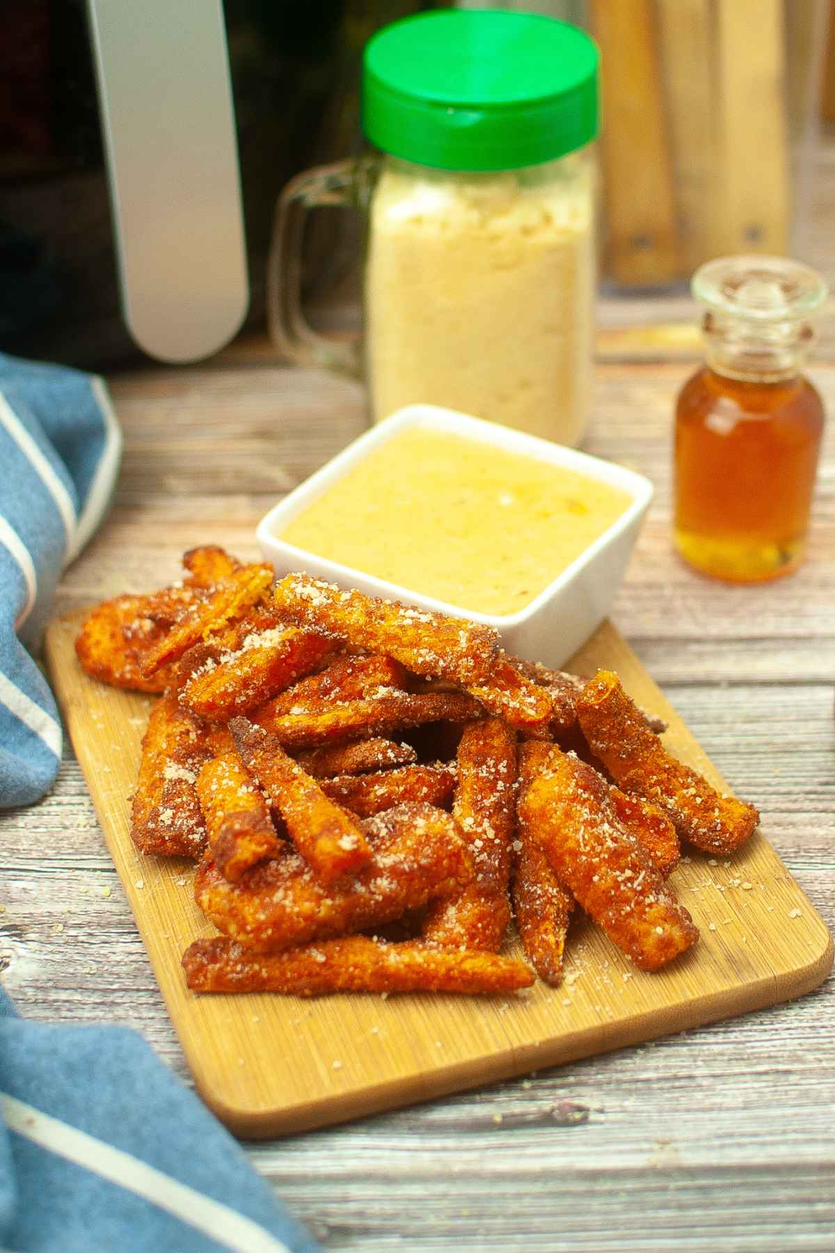 Hero image for Air Fryer Carrot Fries on a wooden board with a bowl of sweet and spicy mayo.