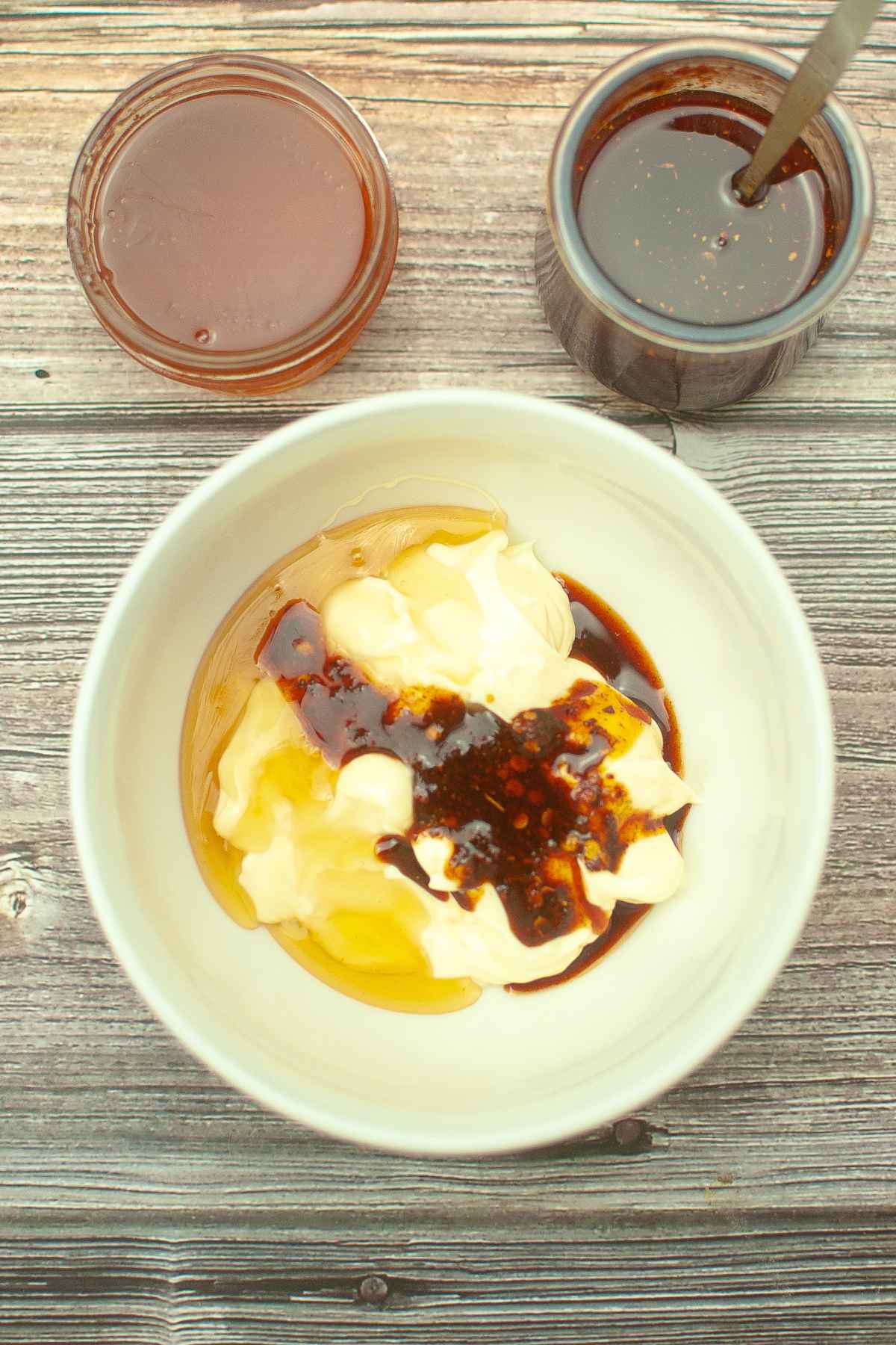 Mayonnaise, honey, and chili oil in bowls and containers.