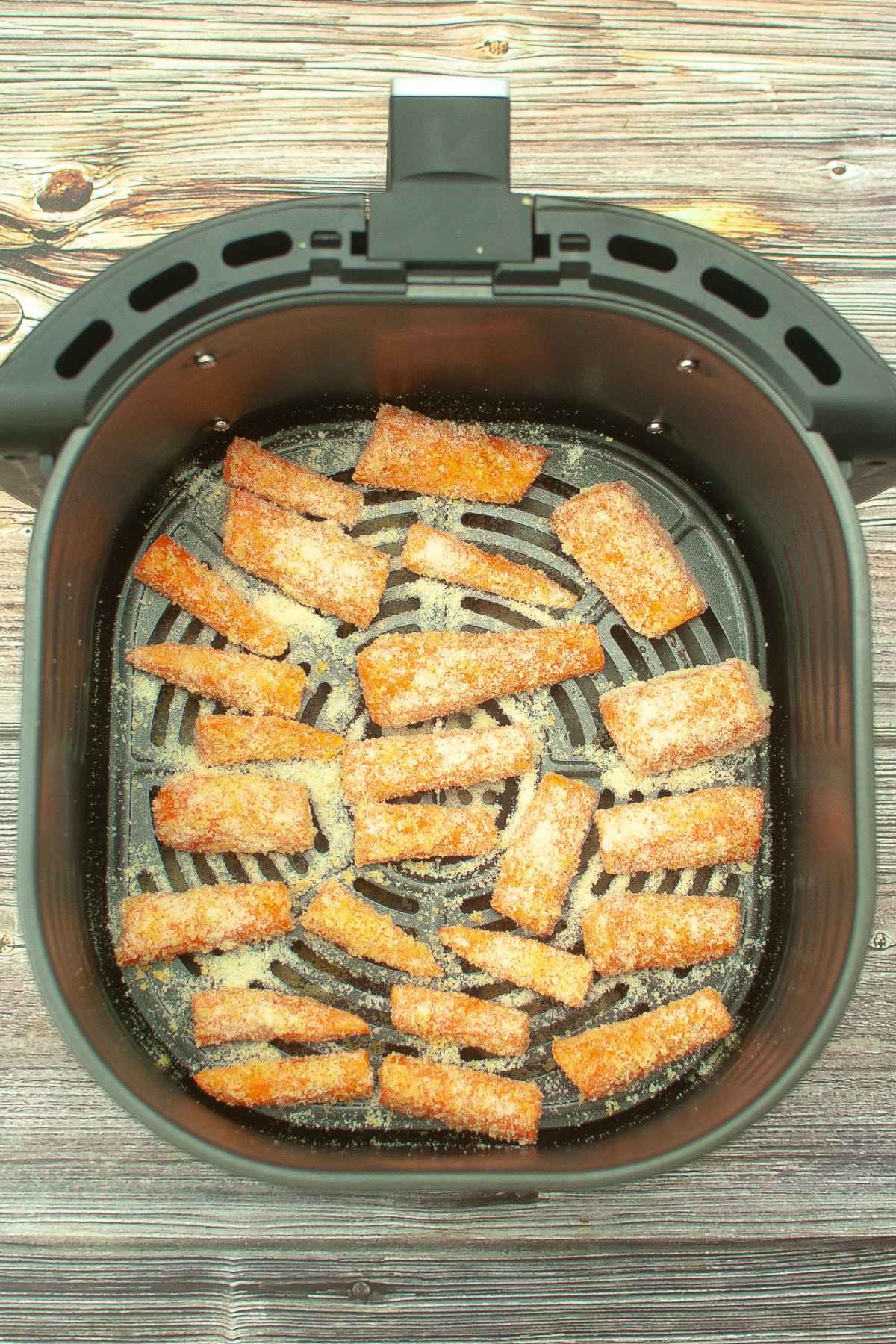 Raw carrot sticks in the air fryer basket.