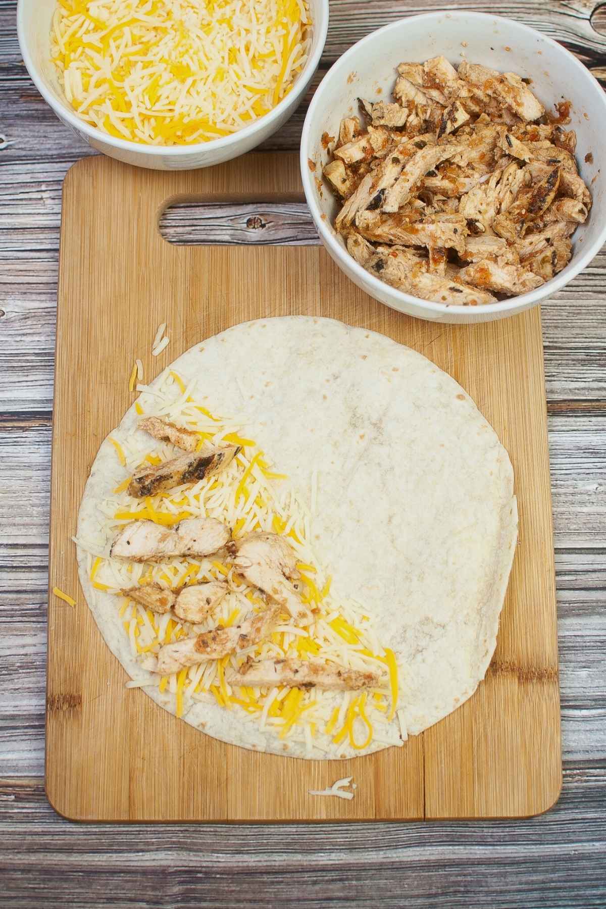 Flour tortilla with cheese and chicken strips on half of the tortilla.