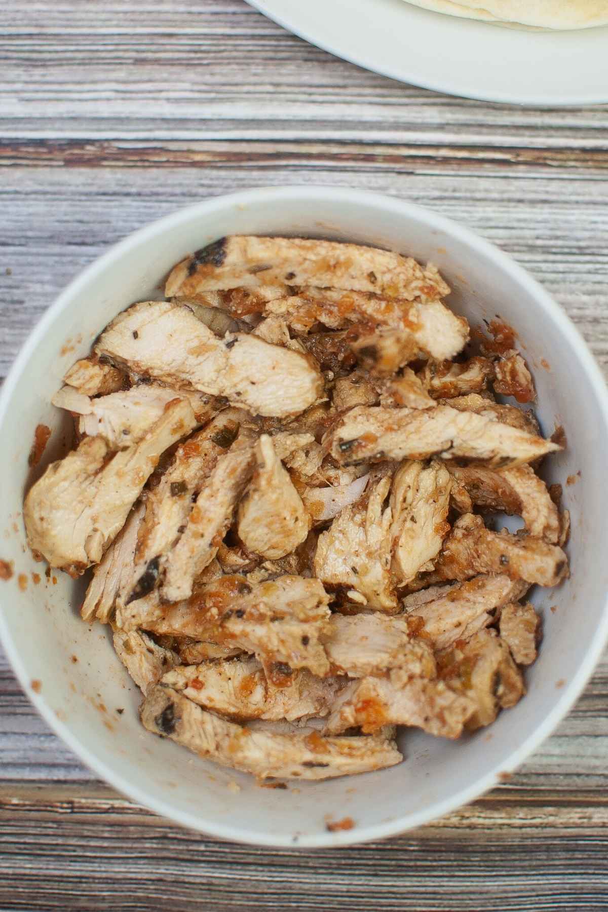 Grilled chicken strips with salsa in a white bowl.