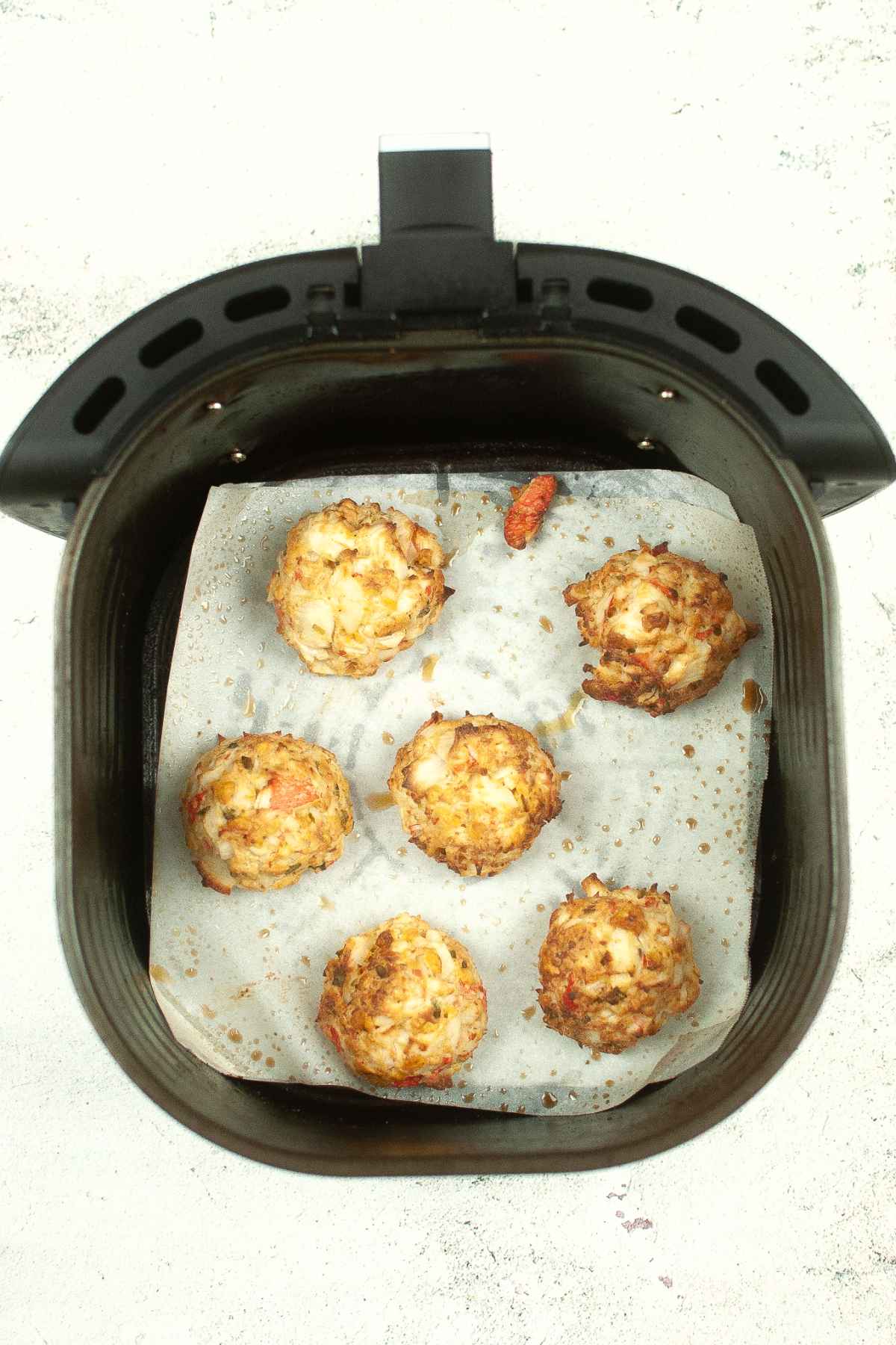Cooked crab cakes in air fryer basket.