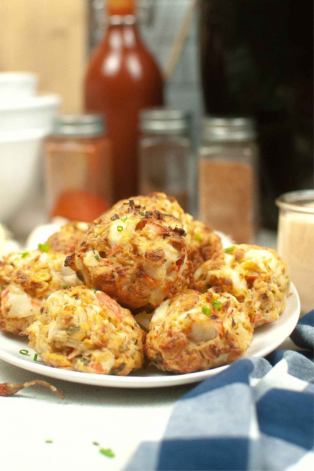 A stack of Air Fryer Crab Cakes garnished with chopped chives on a white plate.