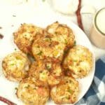 Crab cakes stacked on a white plate.