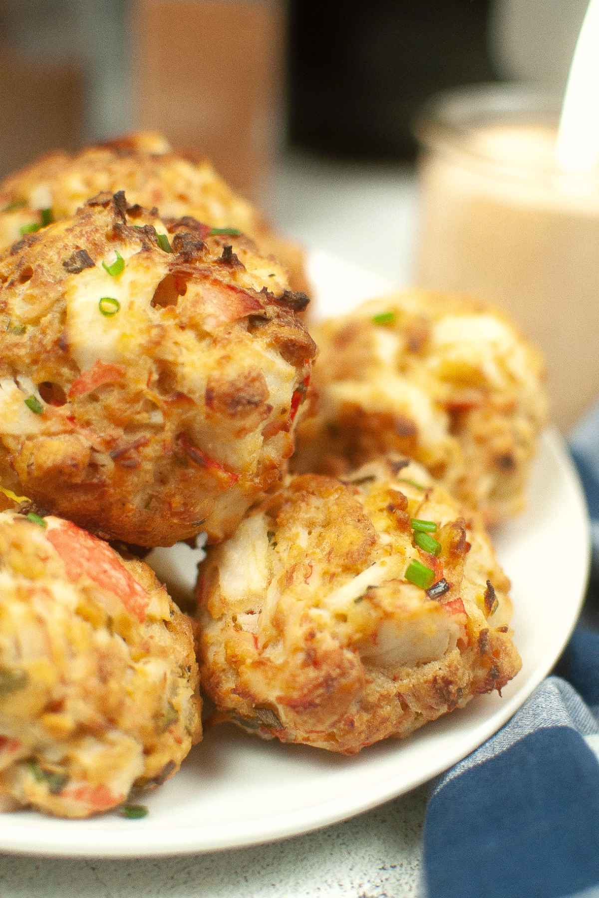 Up close image of air fryer crab cakes garnished with chives on a white plate