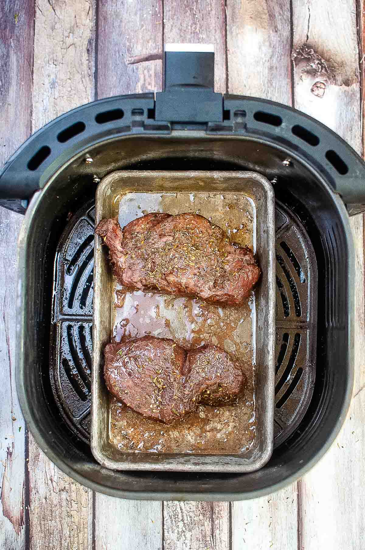 Cooked steaks in pan in air fryer.