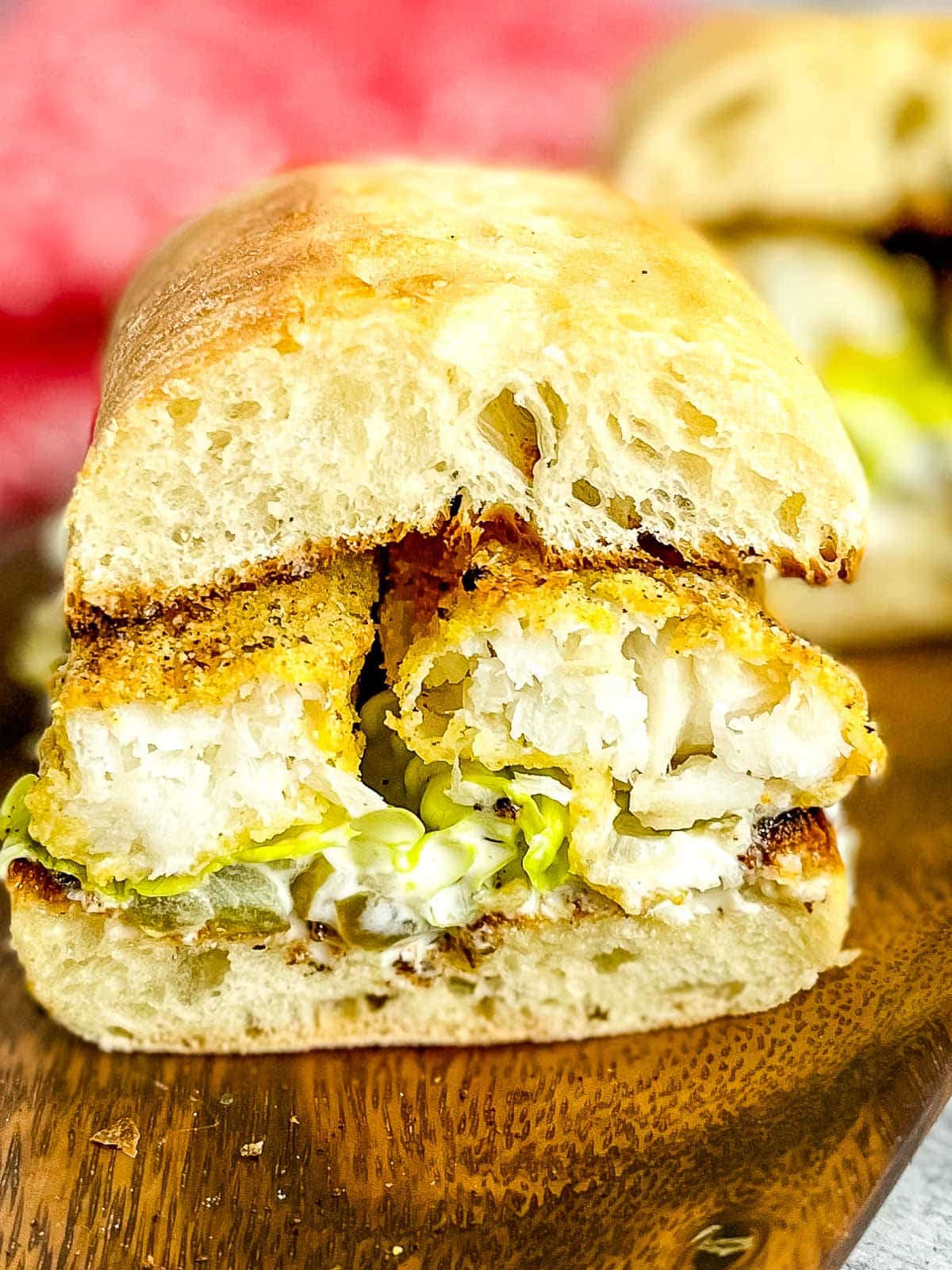 A fish sandwich that has been cut in half on a brown tray.