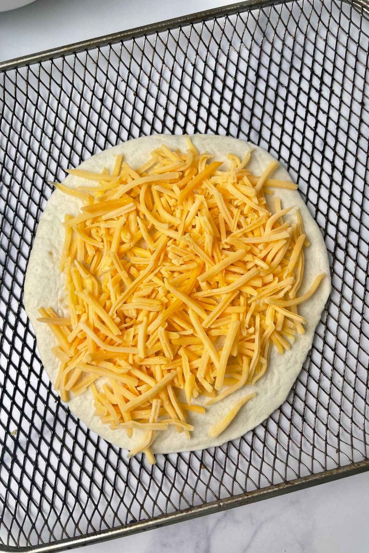 Flour tortilla topped with shredded cheese.