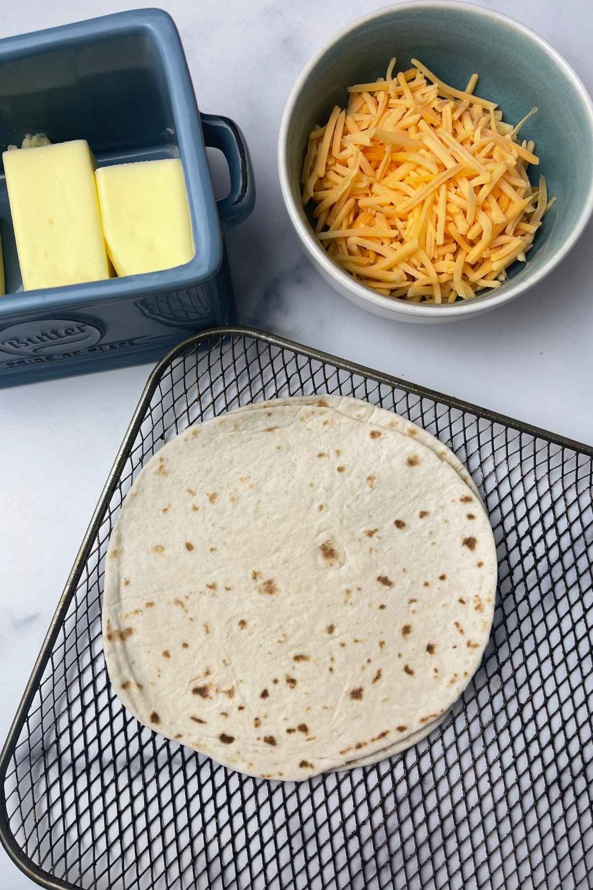 Butter, shredded yellow cheese, and two flour tortillas.