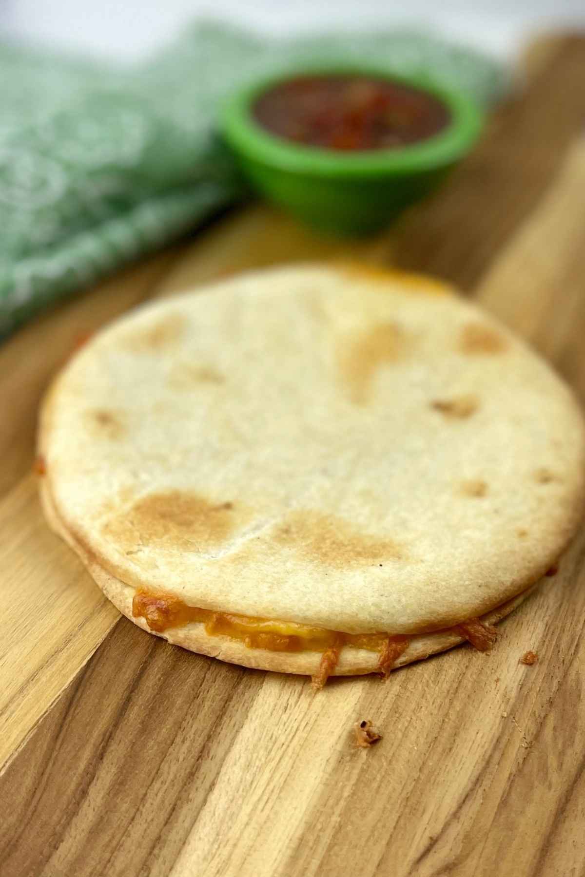 Uncut air fryer quesadilla with salsa in the background.s