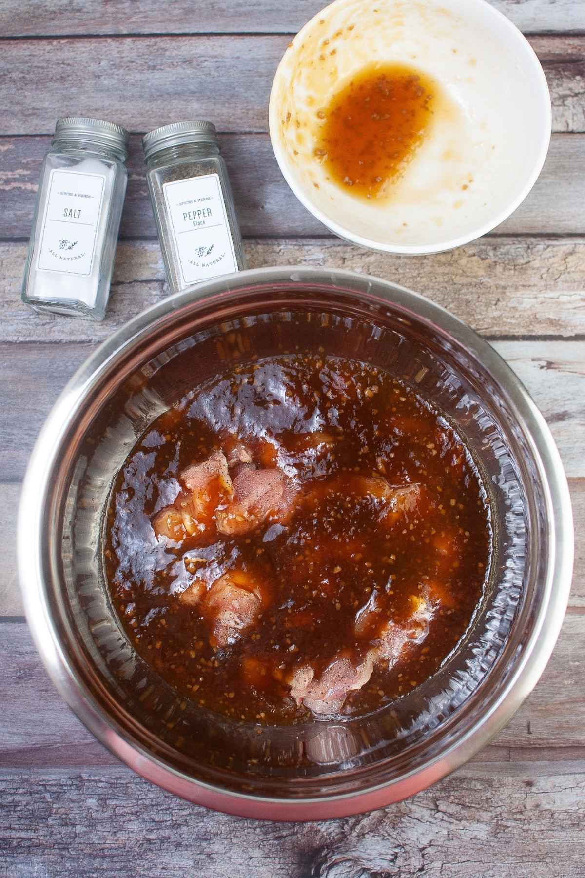 Raw chicken in a bowl with marinade.