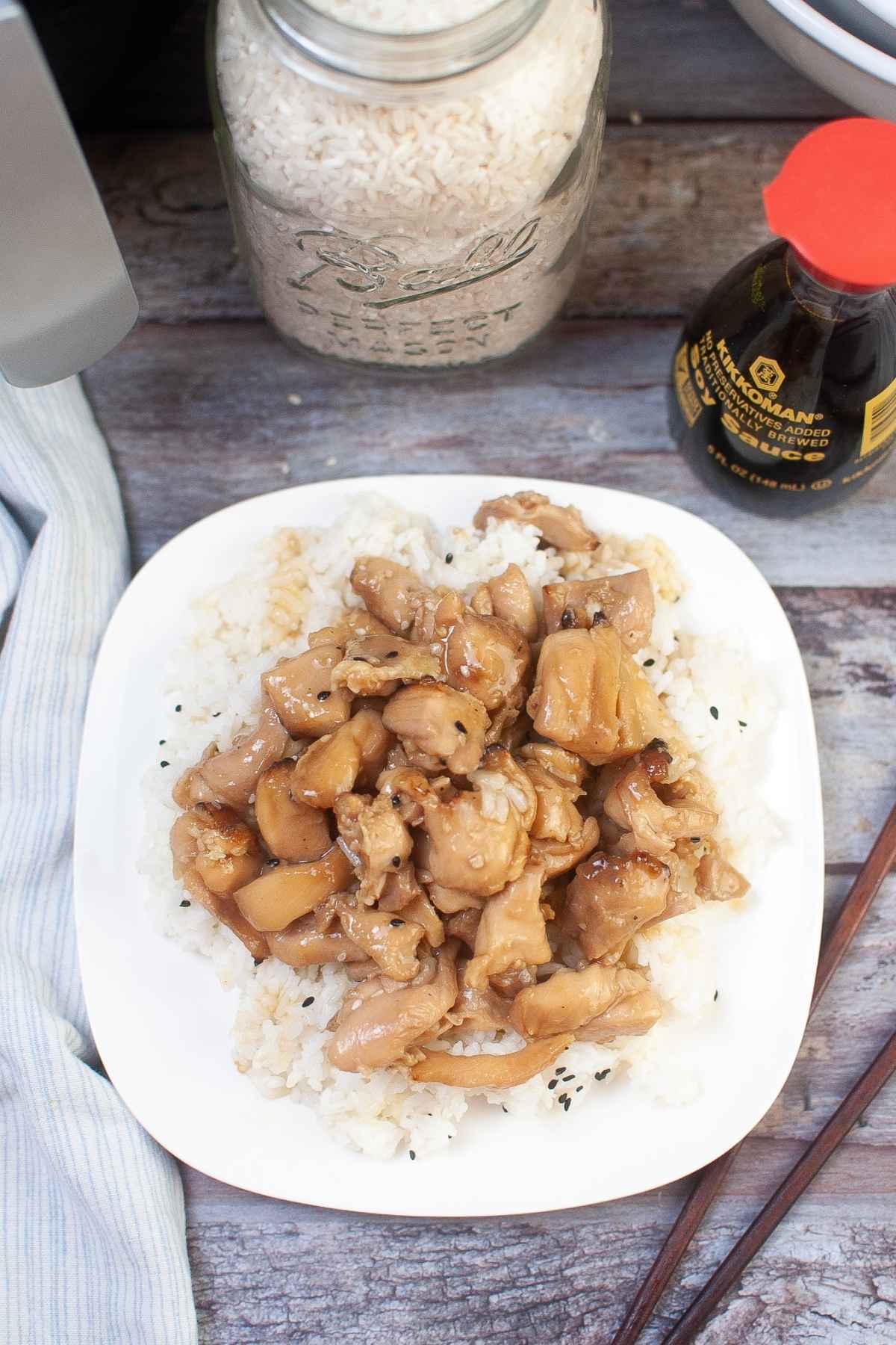 Overhead shot of air fryer teriyaki chicken on a bed of rice on a white plate.