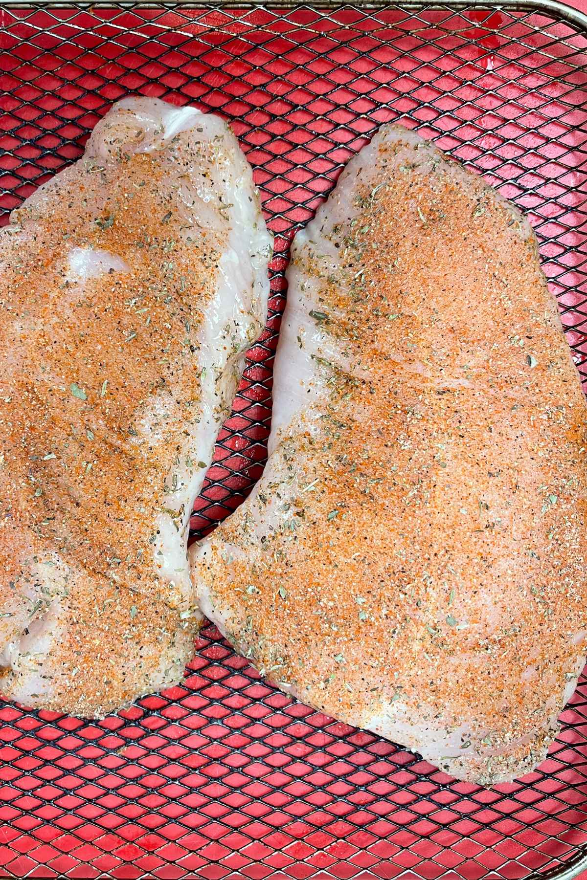 Seasoned turkey breasts on an air fryer tray.