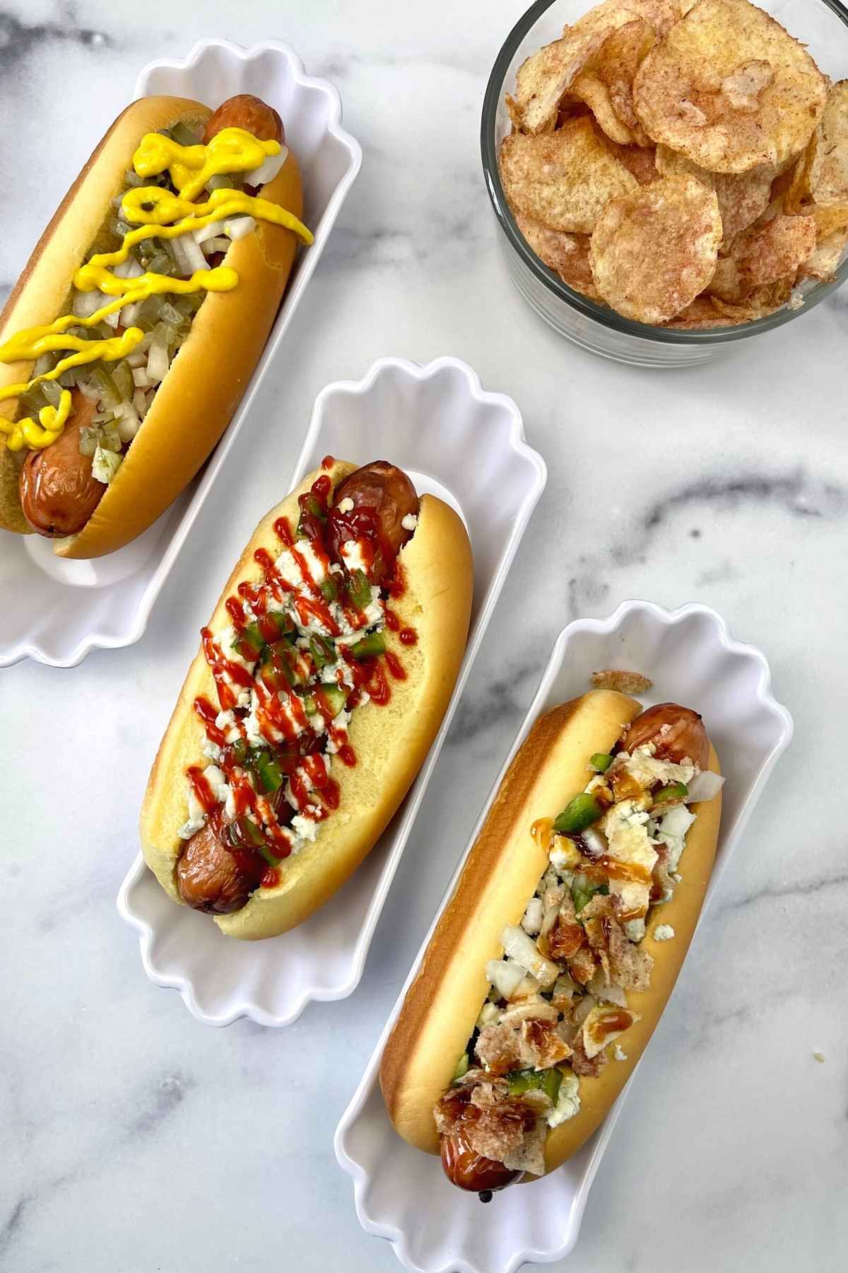 Three hot dogs in buns with different toppings.