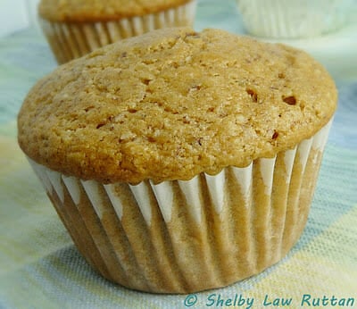 Two baked date muffins with parchment paper muffin liners.