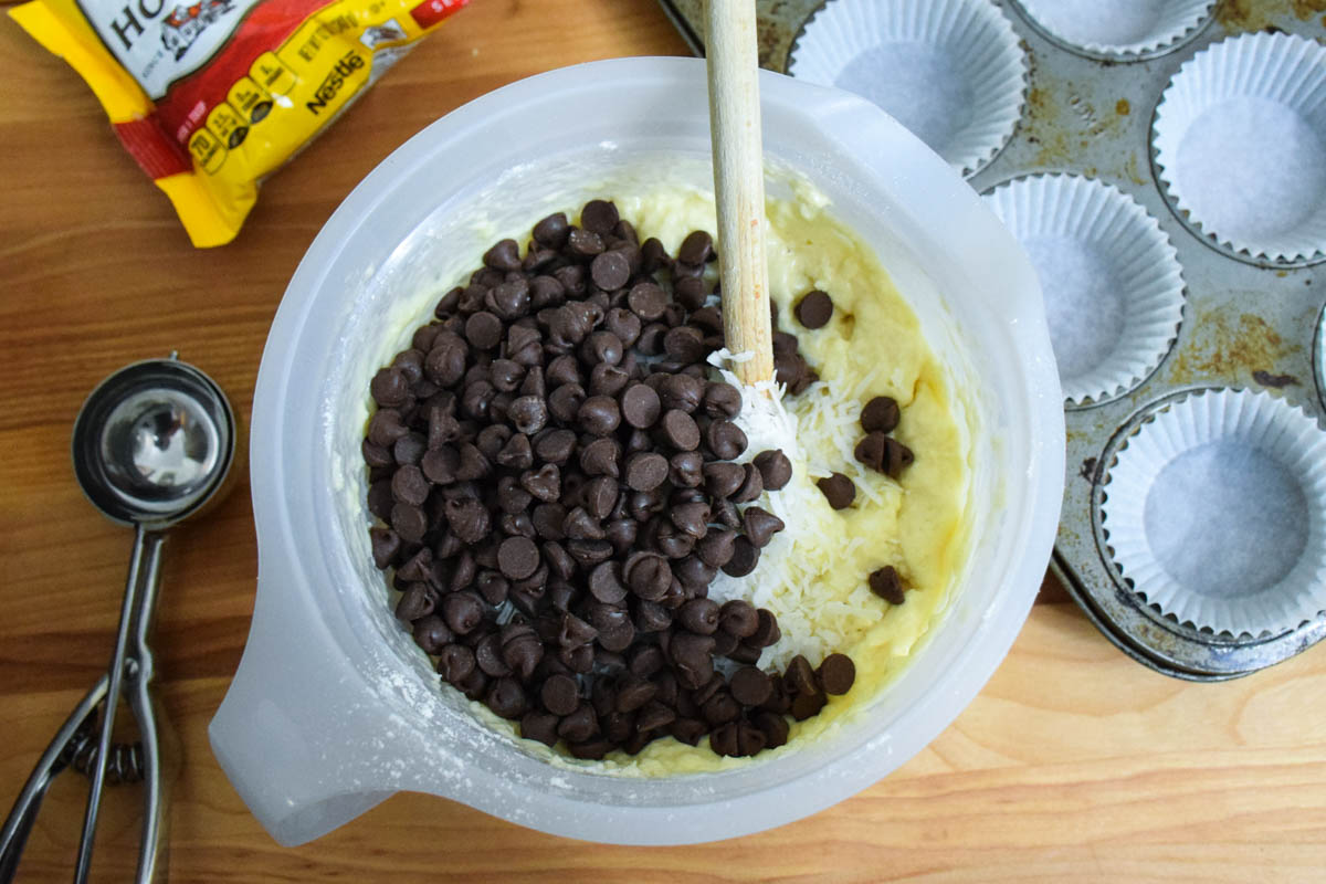 Muffin batter with chocolate chips on top and a spoon in the batter.