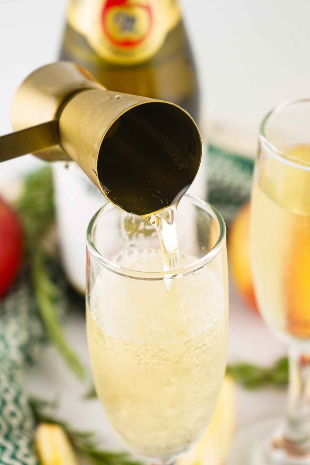 Pouring champagne from jigger into glass.