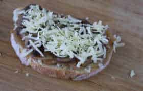 one slice of bread with the cheese, caramelized onion, mushroom and another cheese layer assembled before placing on the grill.