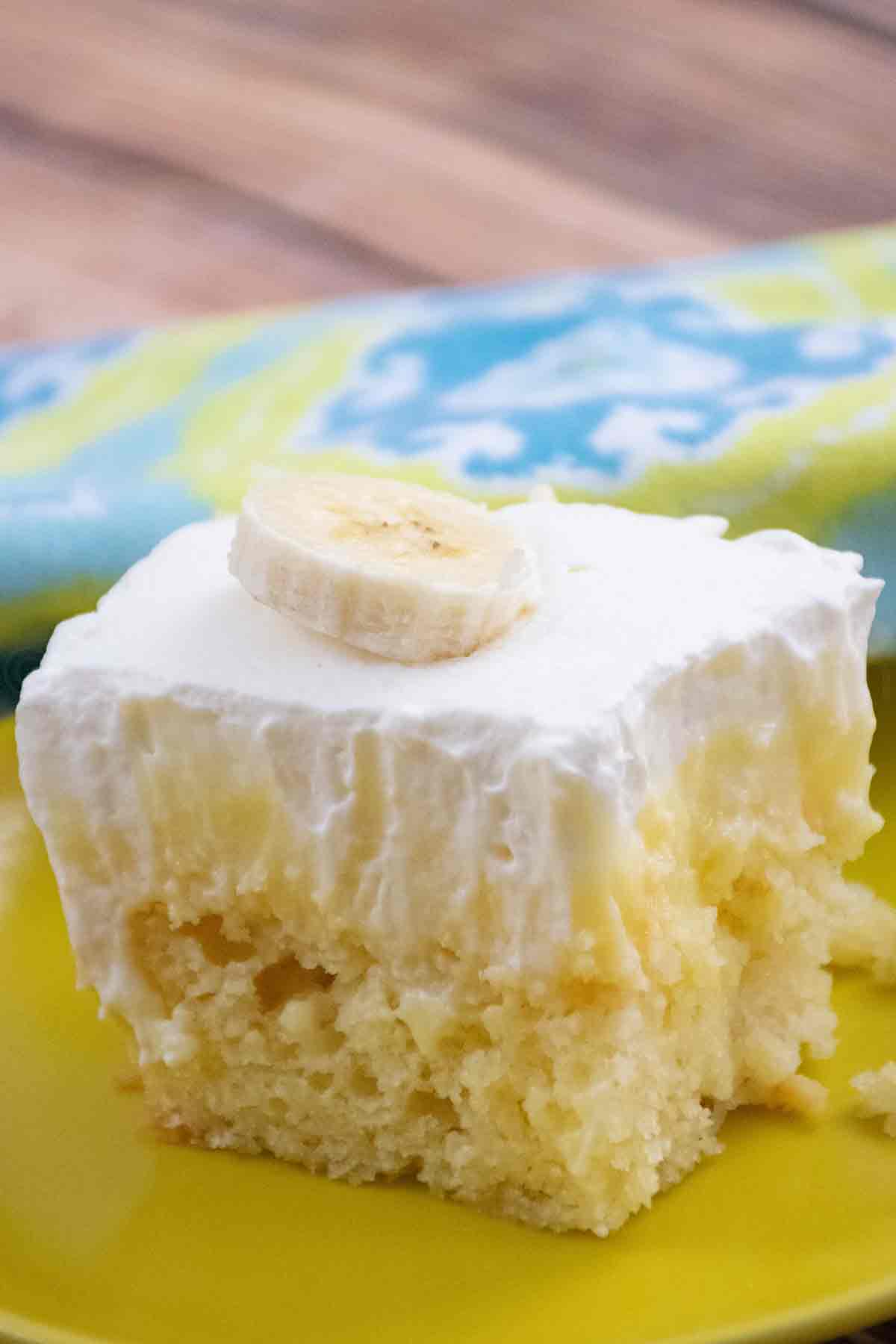 A piece of Banana Pudding Poke Cake on a yellow plate.