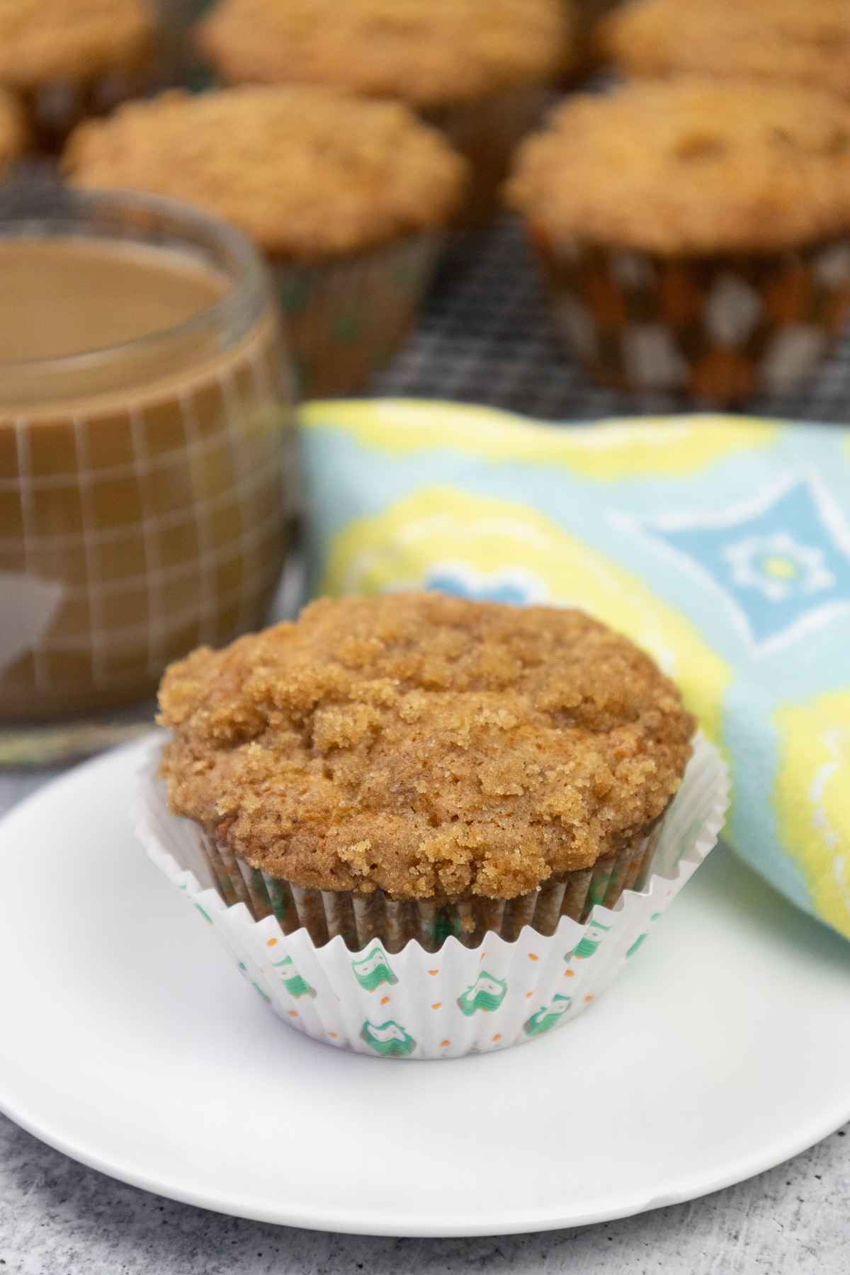Angled side view of banana crumb muffin in a muffin wrapper on a plate.