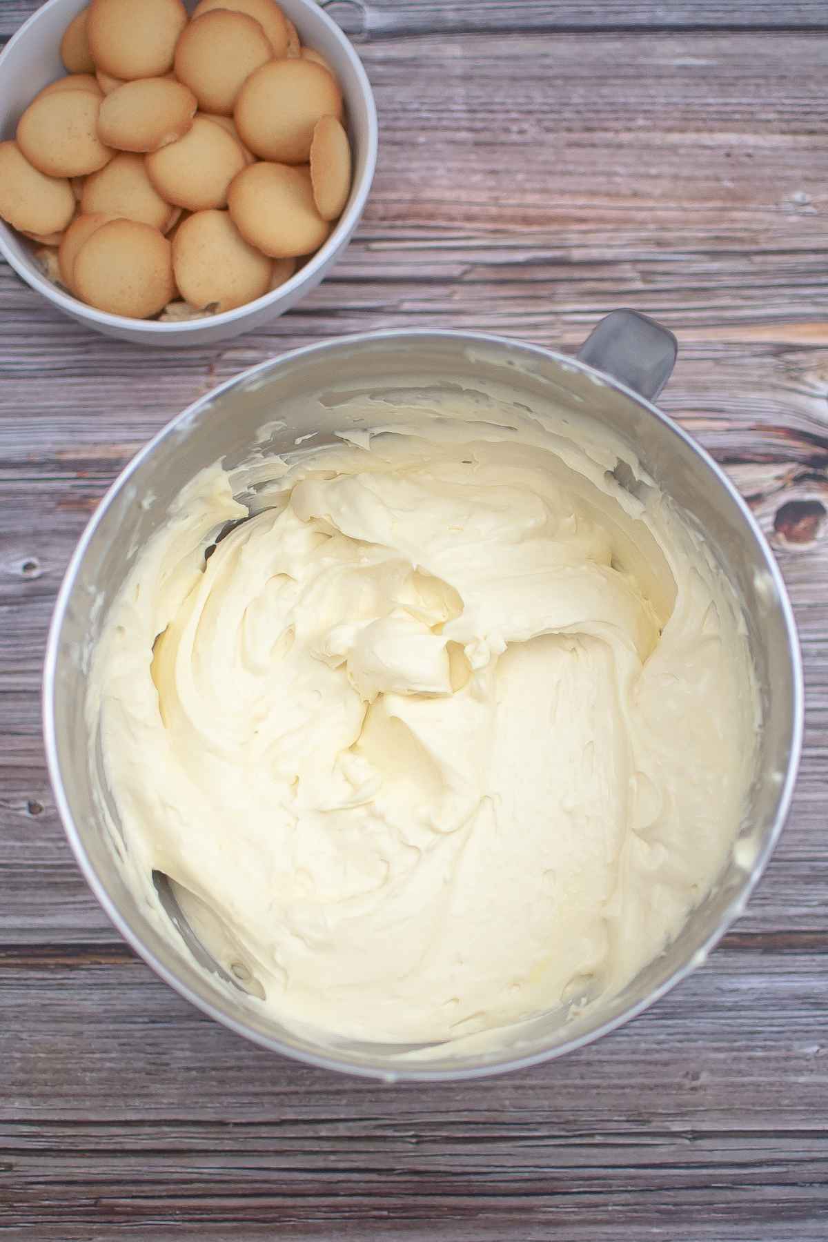 Cheesecake mixture with a bowl of vanilla wafer cookies above the filling mixture.