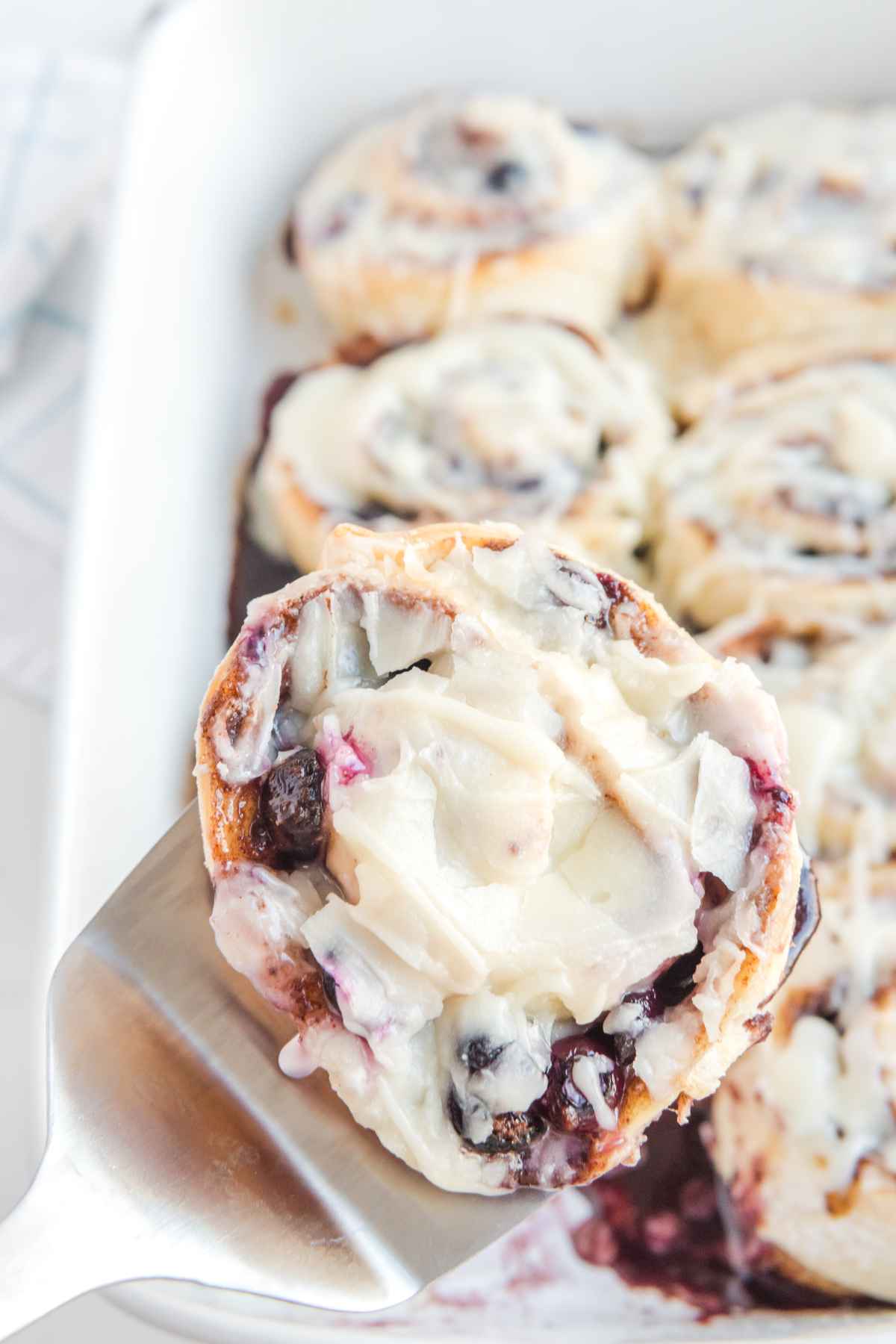 One Blueberry Cinnamon Roll with cream cheese icing over head image.