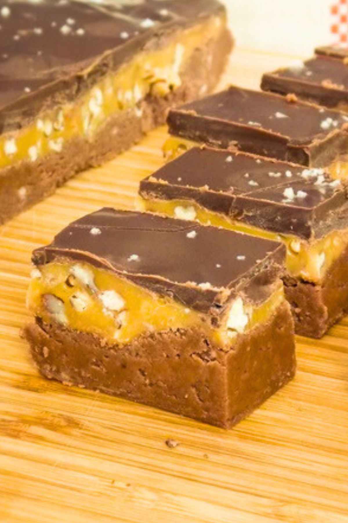 Upclose image for Bourbon Fudge recipe showing a chocolate fudge layer, a bourbon caramel praline layer, and dark chocolate topped with sea salt.