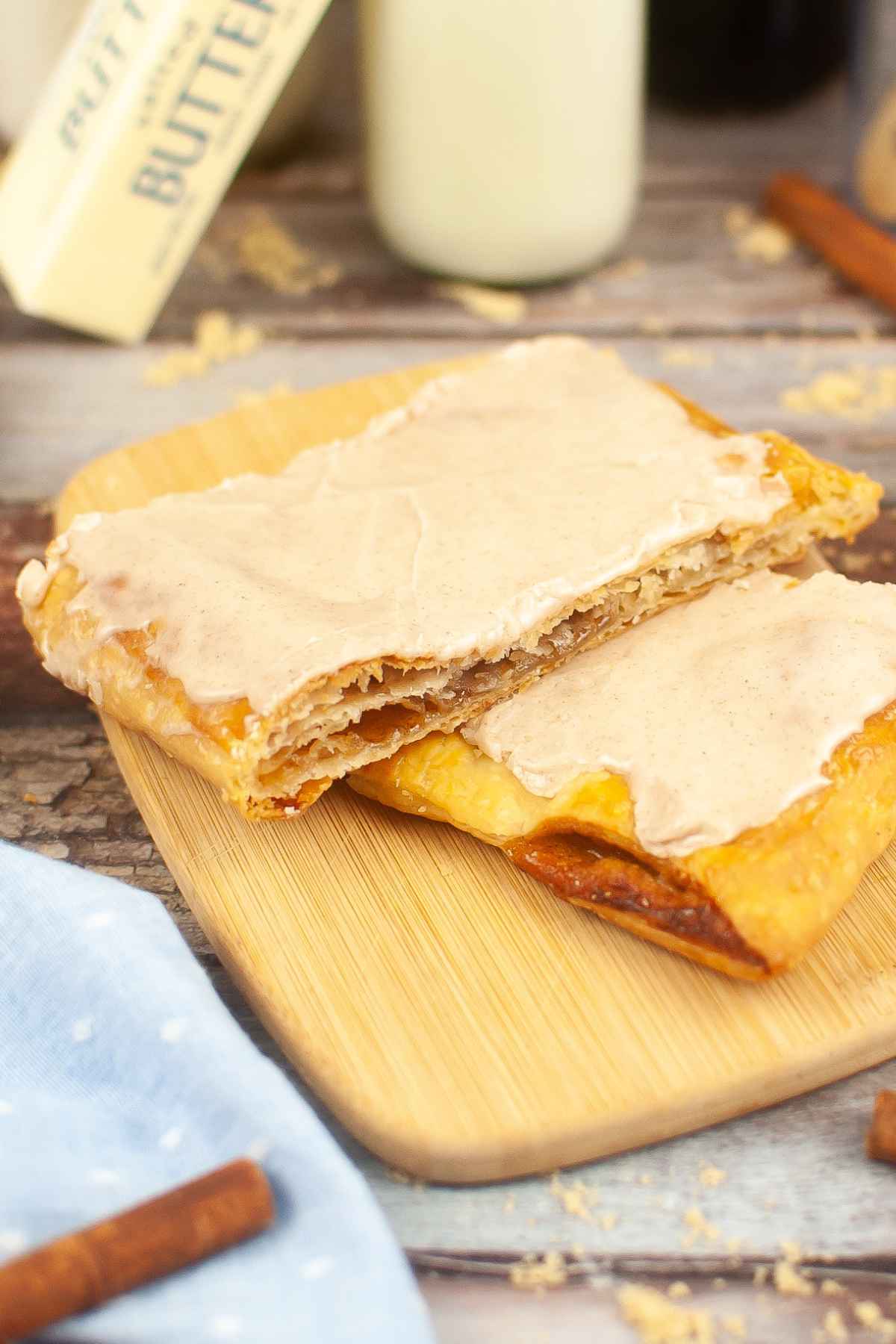 Two Homemade Brown Sugar Cinnamon Pop Tarts stacked on top of each other on a wooden cutting board.