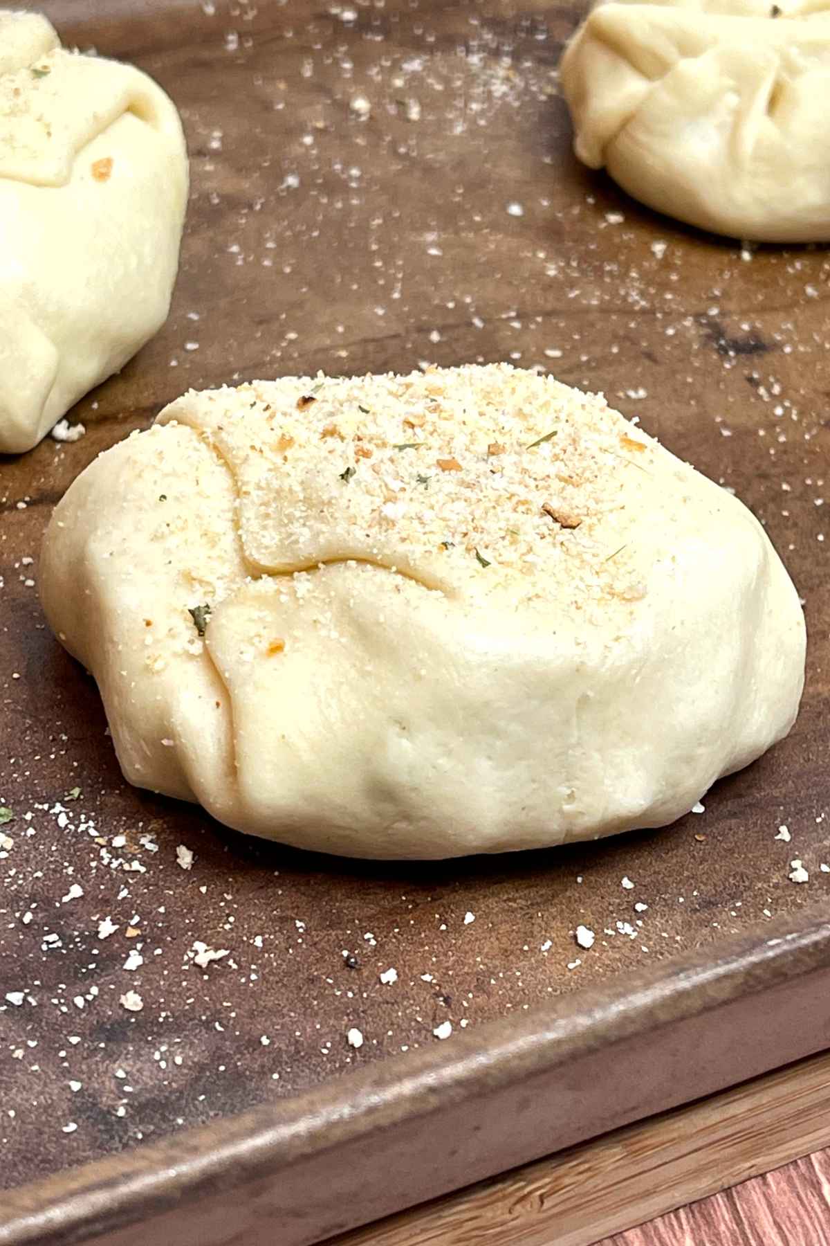 Chicken filling wrapped in pastry on a baking stone sprinkled with bread crumbs.