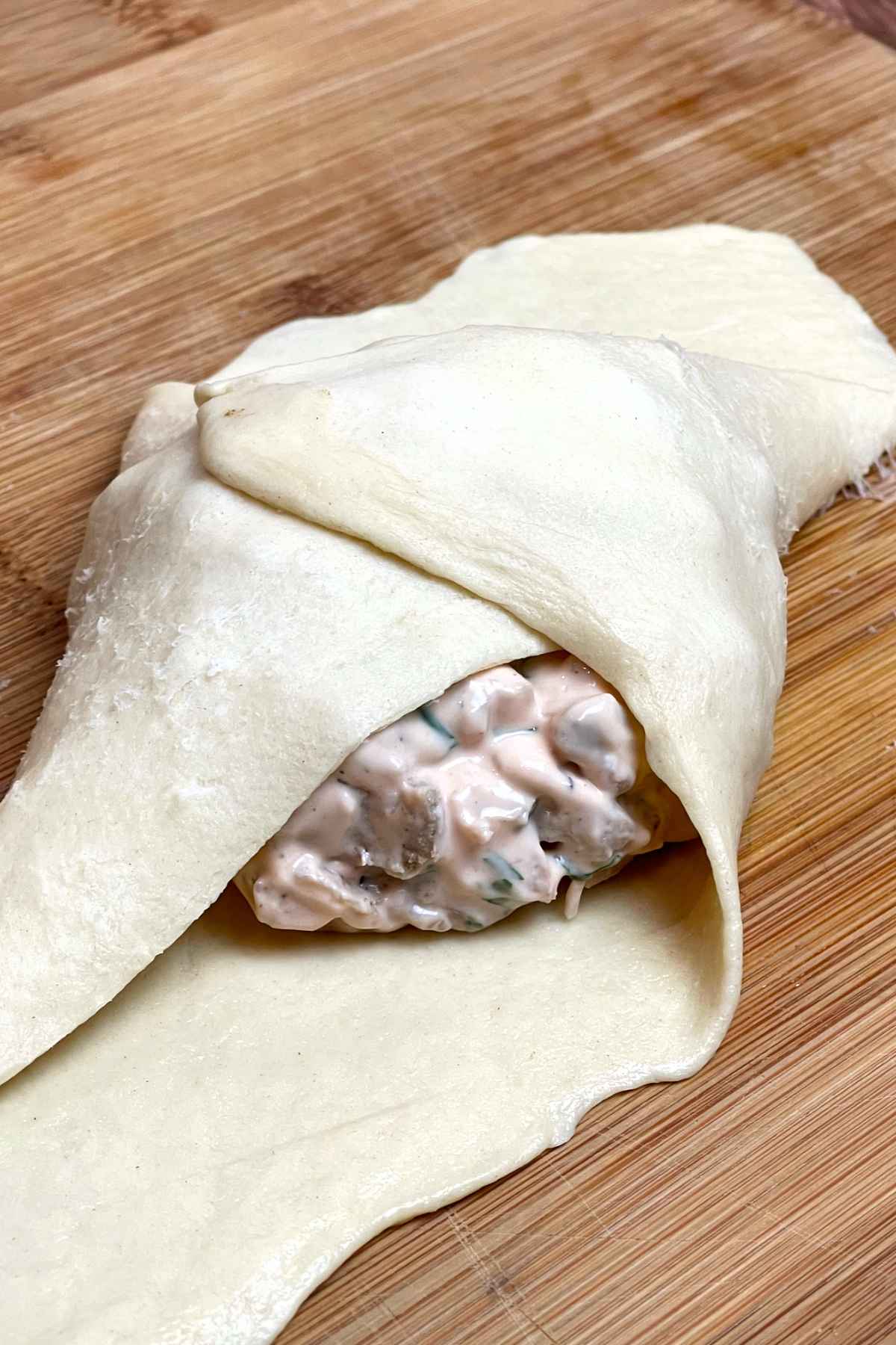 Wrapping the crescent dough around the chicken filling.