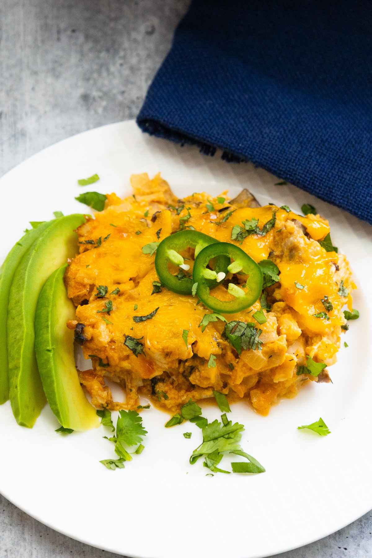 Overhead image of buffalo chicken casserole garnished with two jalapeno pepper slices and side of avocado.