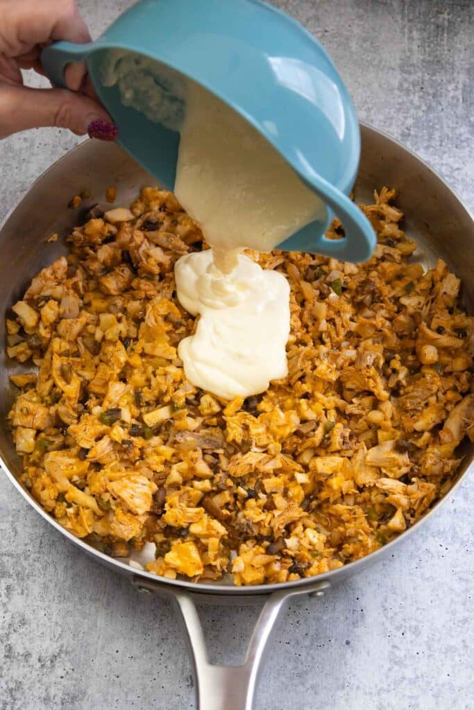 Pouring the sauce into the buffalo cauliflower mixture.