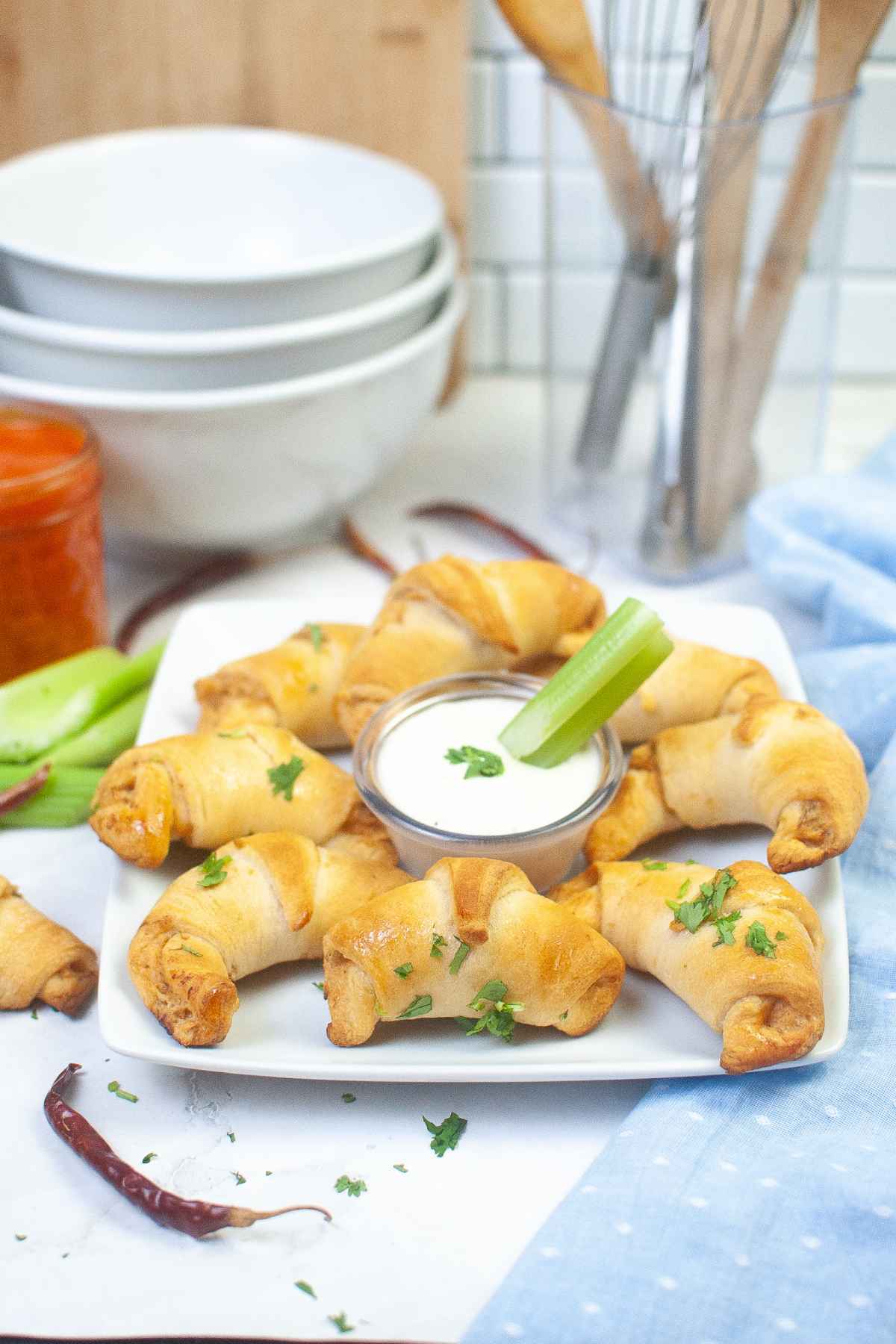 Buffalo Chicken Crescent Rolls on a white plate with celery and dip in the center of the plate