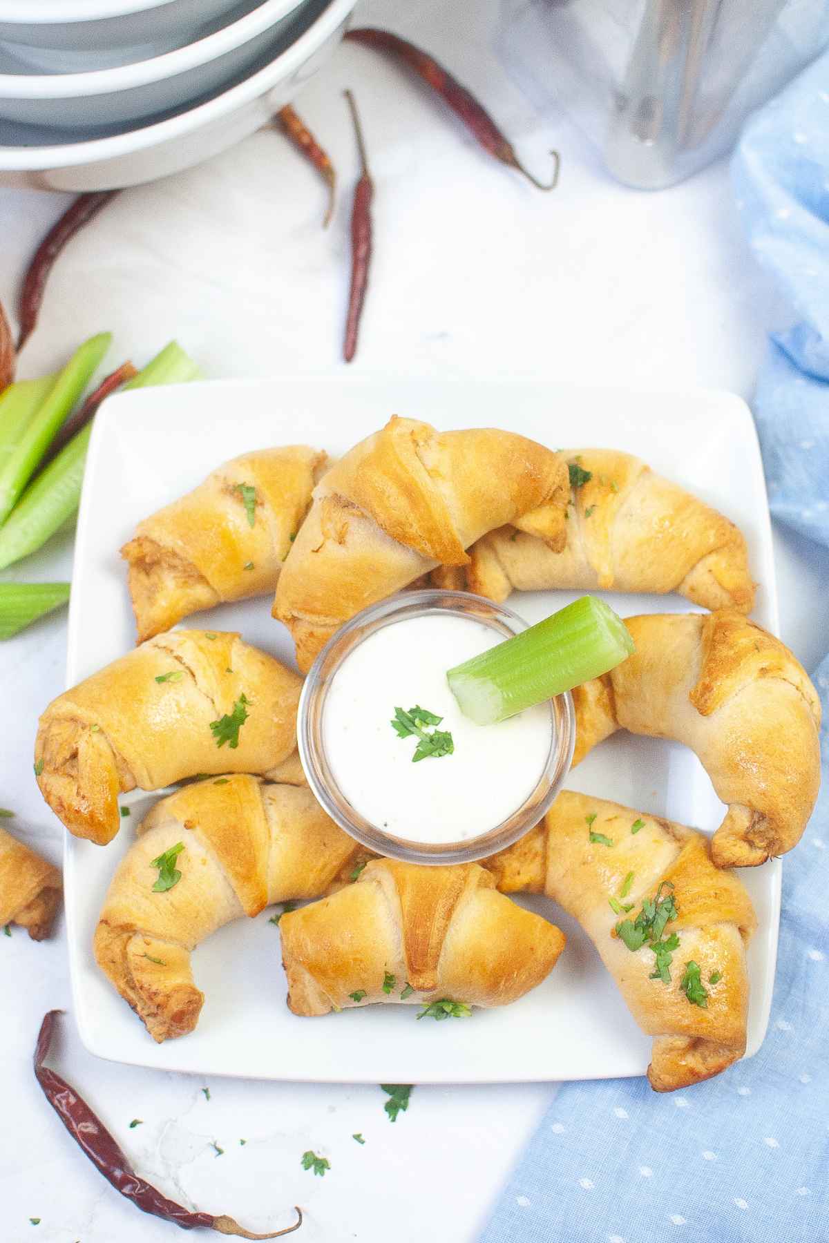 Eight crescent roll appetizers on a white plate with dip in the center.