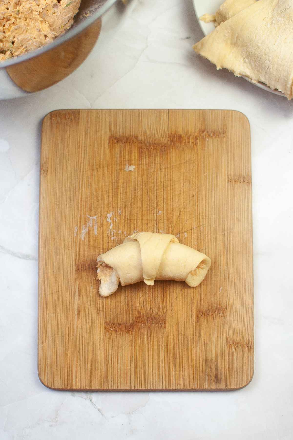 Single chicken roll up on a wood board.