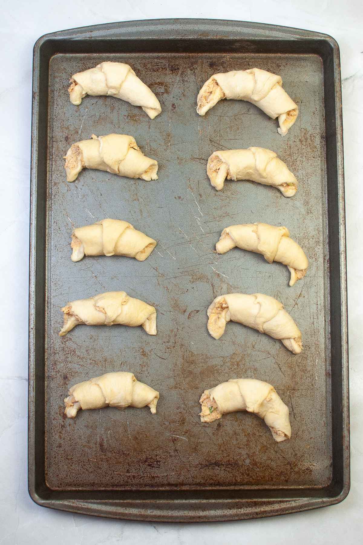 Unbaked crescent rolls on baking sheet.