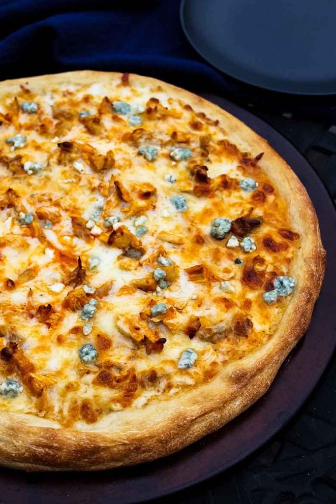 Overhead shot of buffalo chicken pizza recipe on a pizza stone unsliced