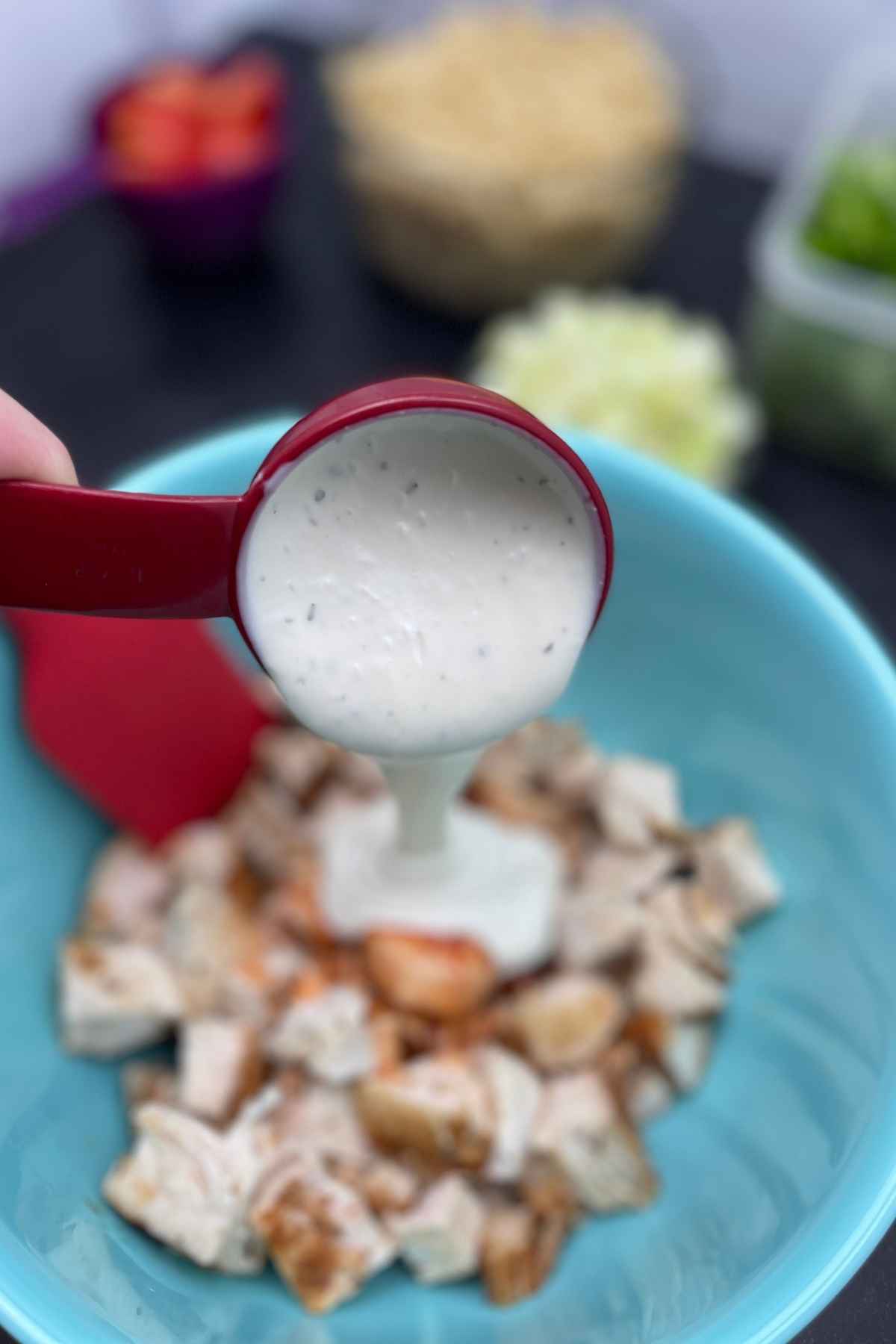 Pouring the ranch dressing over the chicken mixture.