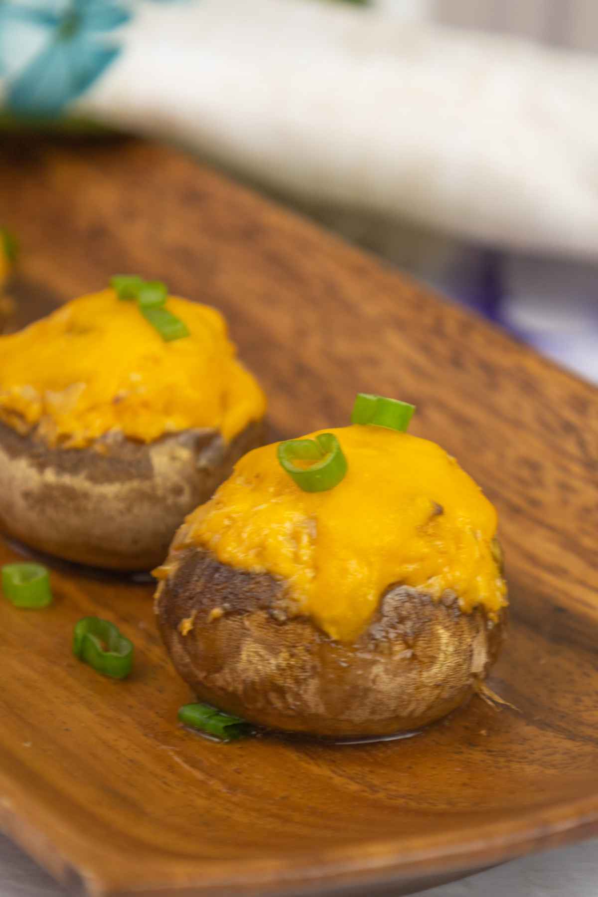 Baked buffalo chicken stuffed mushrooms on a brown tray garnished with green onion tops.