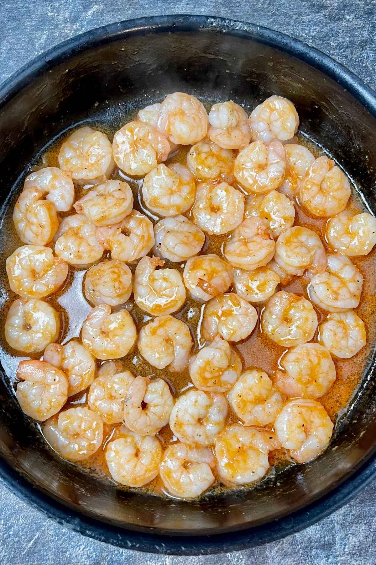 Cooked shrimp in a skillet covered with buffalo sauce.