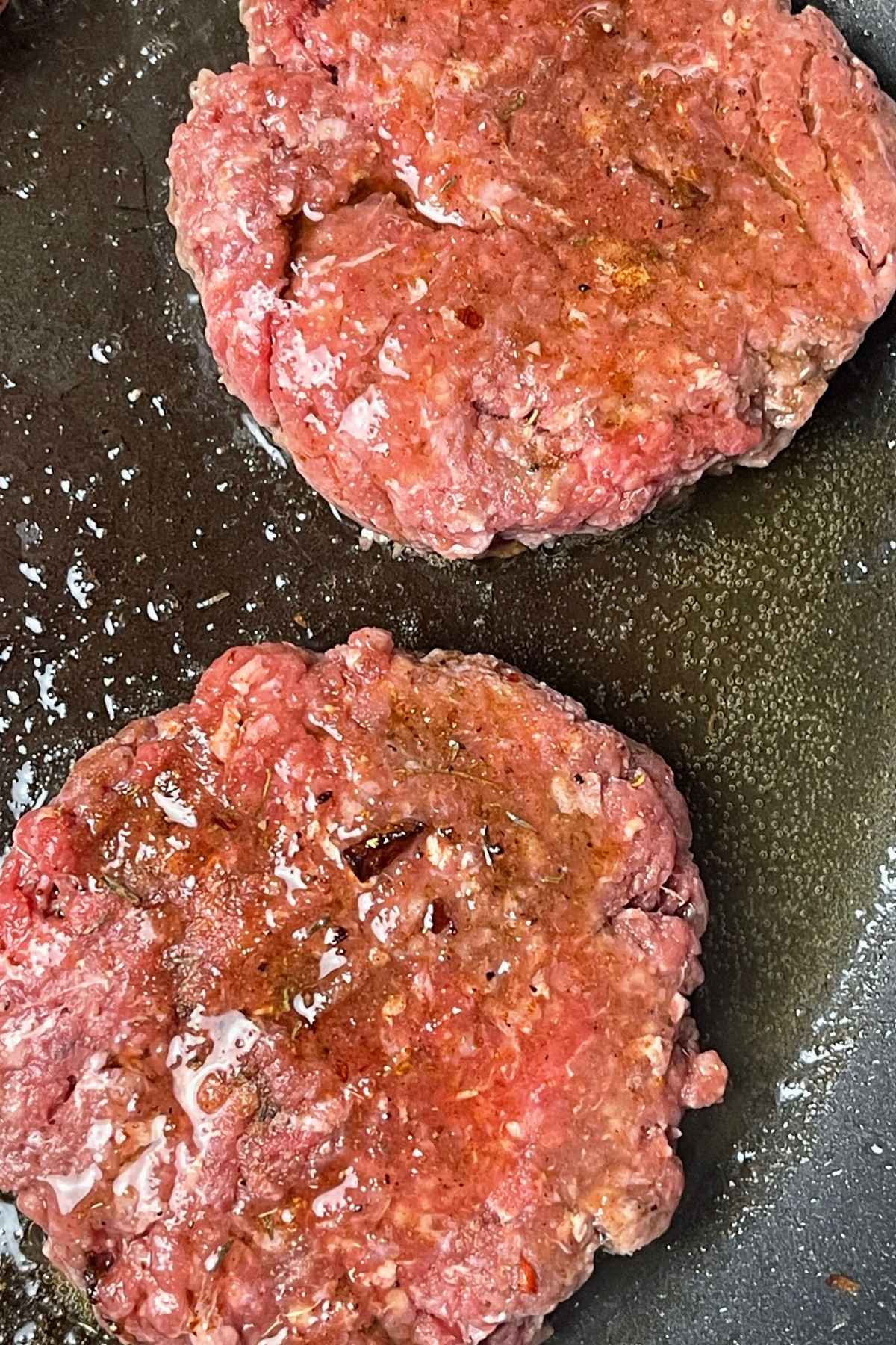 Butter basted burgers cooking in a skillet