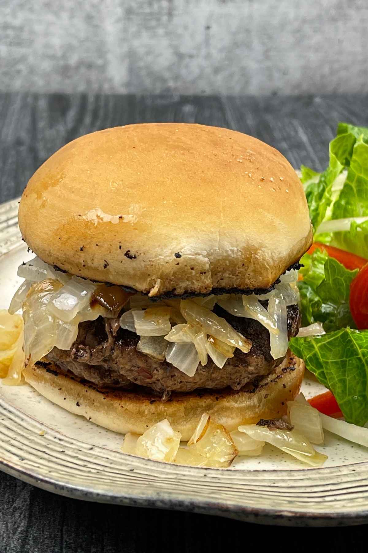 A keto butter burger on a plate with a side green salad.