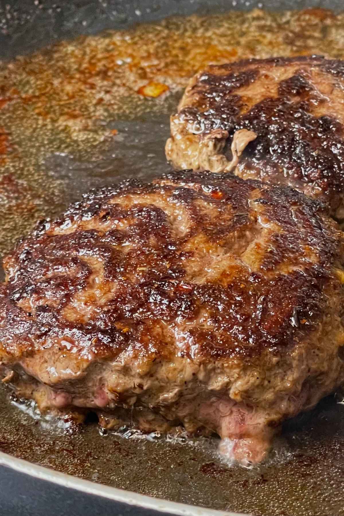 Browned hamburgers in a skillet.