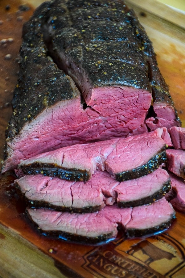 Whole Beef Tenderloin Roast on a cutting board with 3 slices cut from the roast.