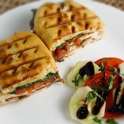 Caprese Panini sandwiches with a side of cucumber tomato salad.