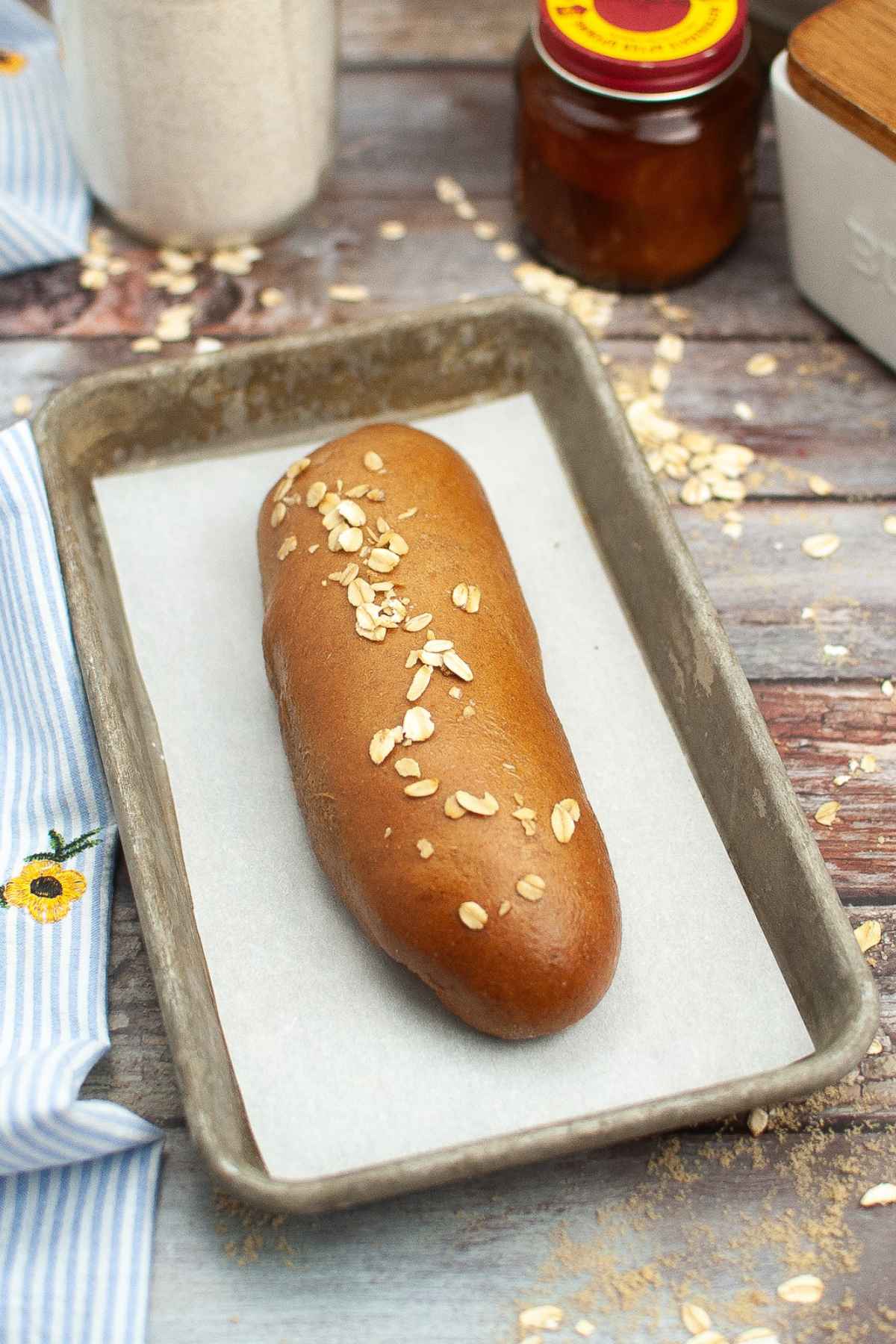 One loaf of cheesecake factory brown bread on a parchment lined baking sheet.