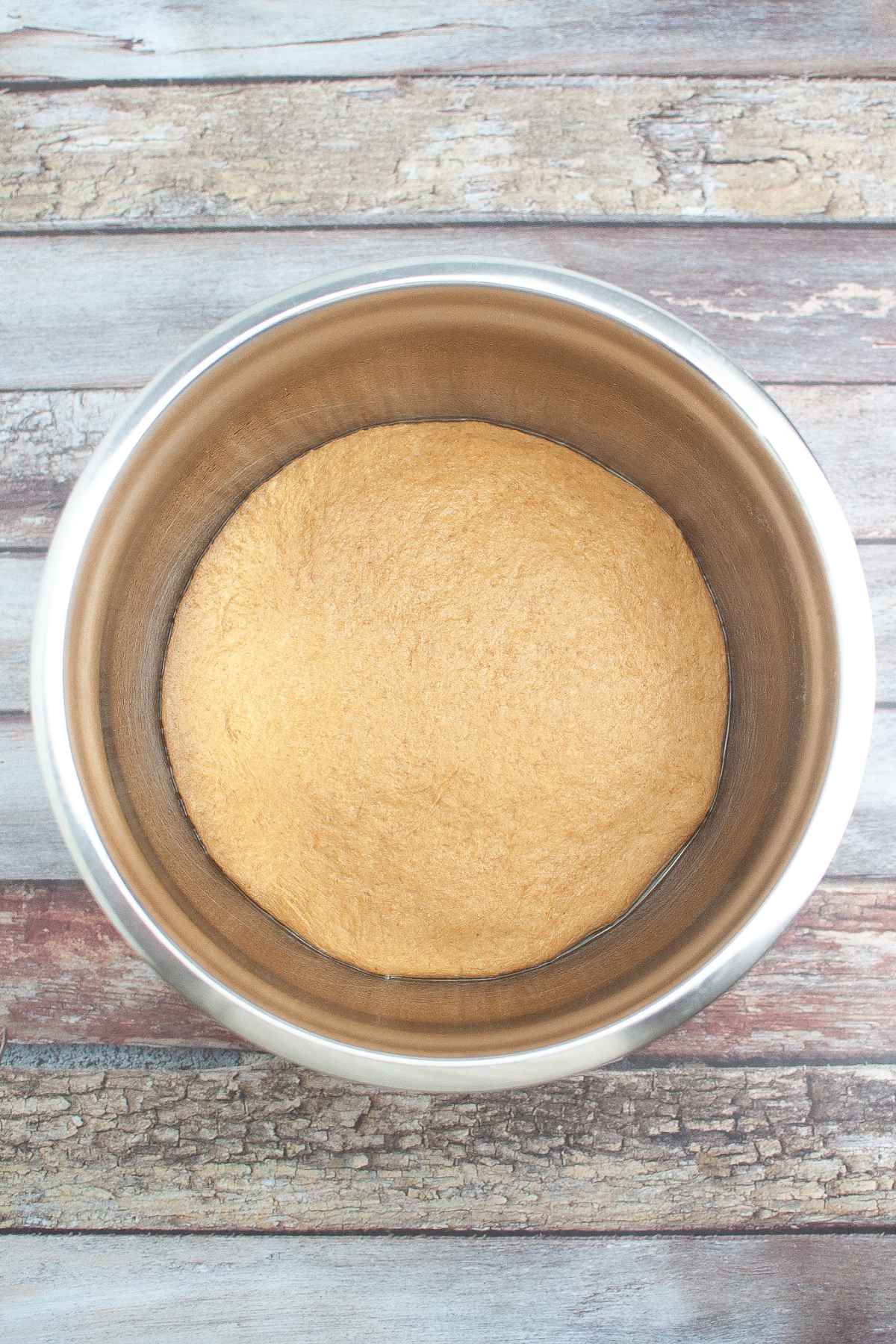 Bread dough rising in an oiled metal bowl.